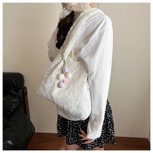 Détail de la dentelle ajourée et du pendentif tulipe sur le sac fourre-tout blanc