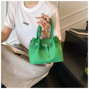 Detail of the bright green woven handbag with buckle design and leather texture