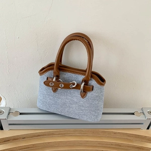Detail of blue denim fabric and brown leather handle on vintage shell-style handbag
