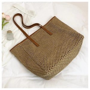 Close-up of straw woven tote bag with brown faux leather straps for summer vacation