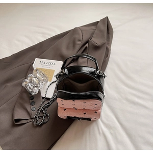 Detail of compact black patent leather and pink seersucker bag with double zipper