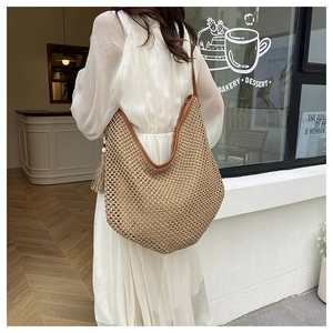 Detail of French straw shoulder bag with brown leather trim and tassel on a model