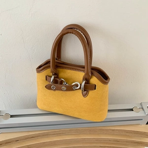 Detail of ginger yellow suede shell bag with dark brown handles and silver metal hardware