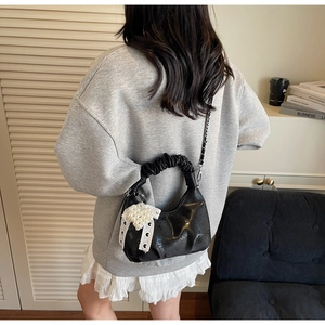 Détail de la poignée plissée et du nœud en perles sur sac à main noir imprimé