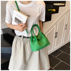 Close-up of green leather handbag with woven pattern texture and adjustable buckle detail