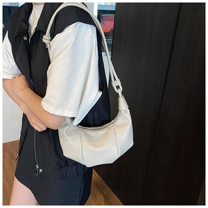 Close-up of cream pleated hobo bag with moon silhouette on model's shoulder