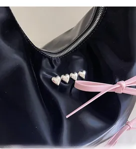 Detail of black leather bag with silver heart studs and pink leather bow ribbon