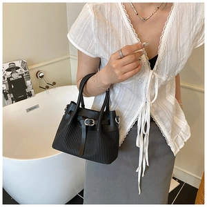Close-up of black bucket bag featuring woven texture and silver buckle detail on leather