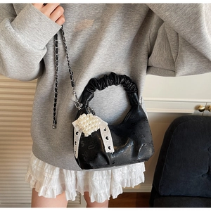Detail of black pleated handbag featuring digital embossed patterns and heart pearl charm