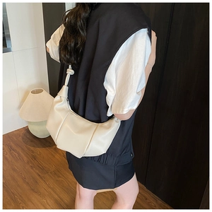 Detail of off-white croissant bag with knotted shoulder strap and pleated leather texture