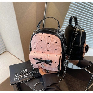 Detail showing pink seersucker backpack with black bows and metal chain strap