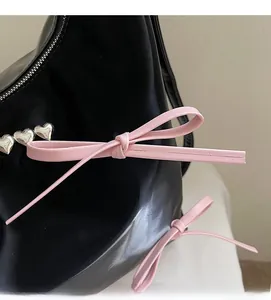 Detail shot of heart-shaped silver rivets and pink leather bow on a black tote bag