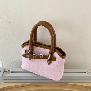 Detailed macro of pink denim texture with brown leather handles and silver metal hardware