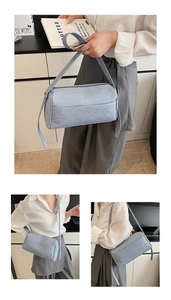 Detail view of light blue denim pillow bag with adjustable crossbody strap and top zipper