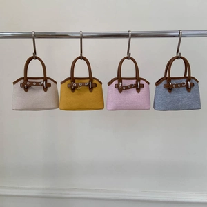 Four textured shell handbags in beige, yellow, pink, and blue with leather handles