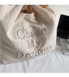Détail du cabas blanc cassé avec broderie Chase My Dreams et fermeture magnétique