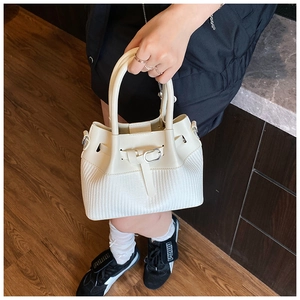 Detail of cream bucket bag showing smooth leather stitching and woven texture pattern