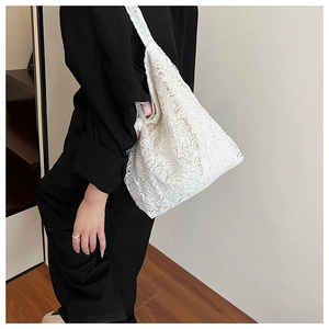 Détail du sac cabas en dentelle blanche avec des motifs floraux semi-transparents élégants
