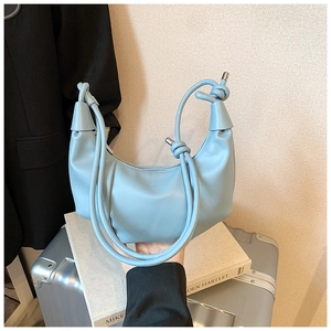 Detail of light blue crescent bag with pleated leather texture and knotted handle