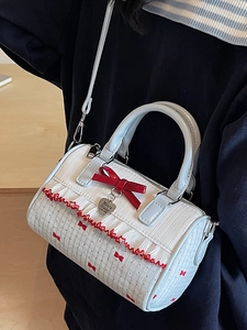 Sweet white Boston bag with red bow prints and heart pendant carried by a model