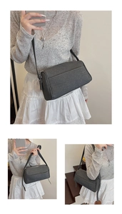Detail showing the dark grey fabric pillow bag with front layered pocket and wide strap