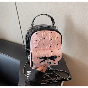 Detail of pink puckered fabric and large black bow with heart pendant on mini bag