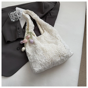 Détail du sac cabas en dentelle blanche avec motifs au crochet et breloque tulipe
