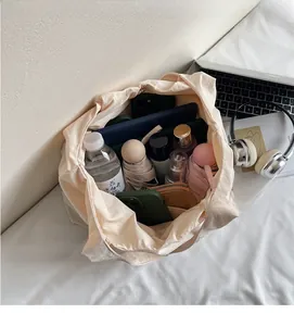 Détail montrant la grande capacité du cabas beige avec divers objets essentiels du quotidien