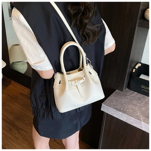 Detailed close-up of cream bucket bag showing V-shaped textured weave and silver hardware