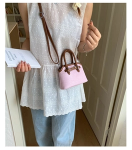 Pink shell handbag with brown handles and silver buckle detail on a white top