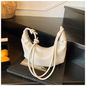 Close-up of minimalist cream crescent bag with pleated leather and knotted shoulder strap
