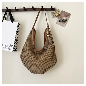 Detailed shot of dark brown straw hobo bag with hollow weave and beaded tassel pendant