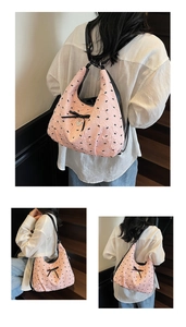 Dettaglio della borsa Hobo rosa con stampa a fiocco nero e ciondolo a cuore su tessuto