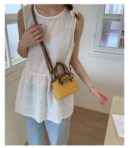 Detail view of mini yellow seashell crossbody bag with brown leather handles worn by model