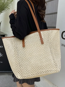 Large beige woven straw tote bag with brown leather straps shown on a female model