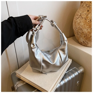 Detail of silver pleated hobo bag with knotted strap on a suitcase
