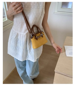 Detail of a mini two-tone shell crossbody bag in ginger yellow suede and brown leather