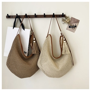 Close-up of bohemian woven straw shoulder bags with leather straps and tassel details