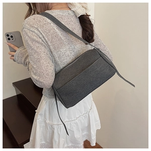 Detail showing the dark grey minimalist pillow bag with textured fabric on a shoulder strap