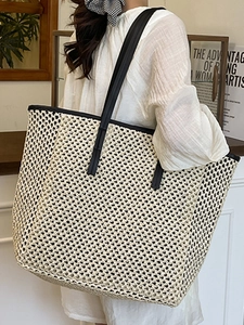 Beige woven straw tote bag with black leather straps for summer beach or commute