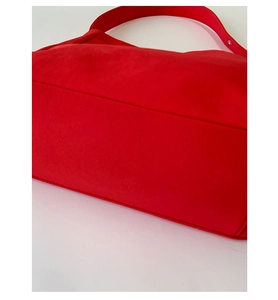Close-up of bright red fabric tote bag showing detailed fiber texture and strap attachment