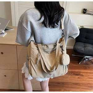 Detail view of khaki canvas tote bag with side pocket and small round hanging pouch