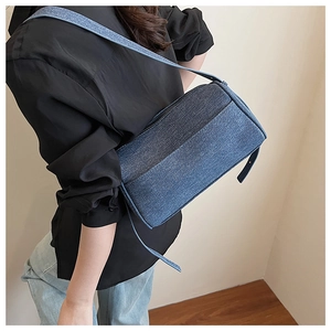 Detail view of the deep blue denim texture and adjustable strap on this chic shoulder bag