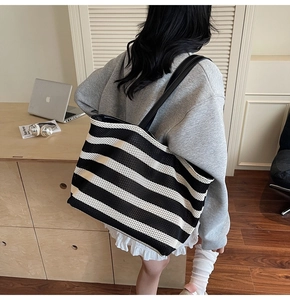 Detail view of large capacity black and white striped canvas tote bag with black straps