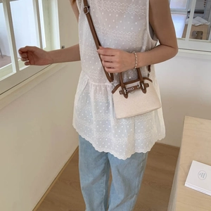 Close-up of beige shell-shaped handbag with brown handles and silver metal clasp detail