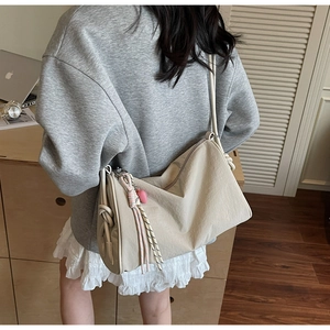 Detail of off-white canvas shoulder bag with pink rope knot and heart charm accessory