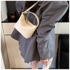 Detail of cream woven leather shoulder bag with gold hardware and Intrecciato texture