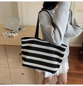 Detail of black and white striped woven tote bag with leather strap in a lifestyle setting