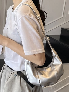 Silver metallic dumpling bag with pleated design and knot strap worn by model