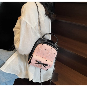Close-up of small black and pink backpack with bow pattern and metal chain strap